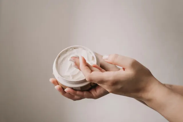 A hand picking cream from a jar